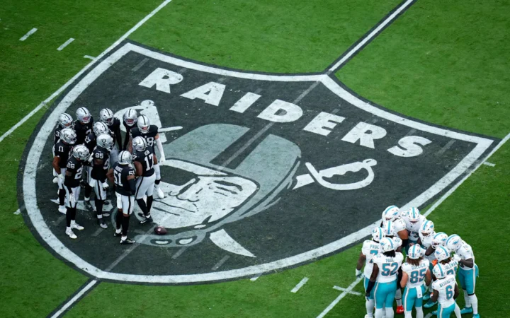 Las Vegas Raiders Defense stand on the Raiders logo in the huddle, as the Dolphins offense do the same