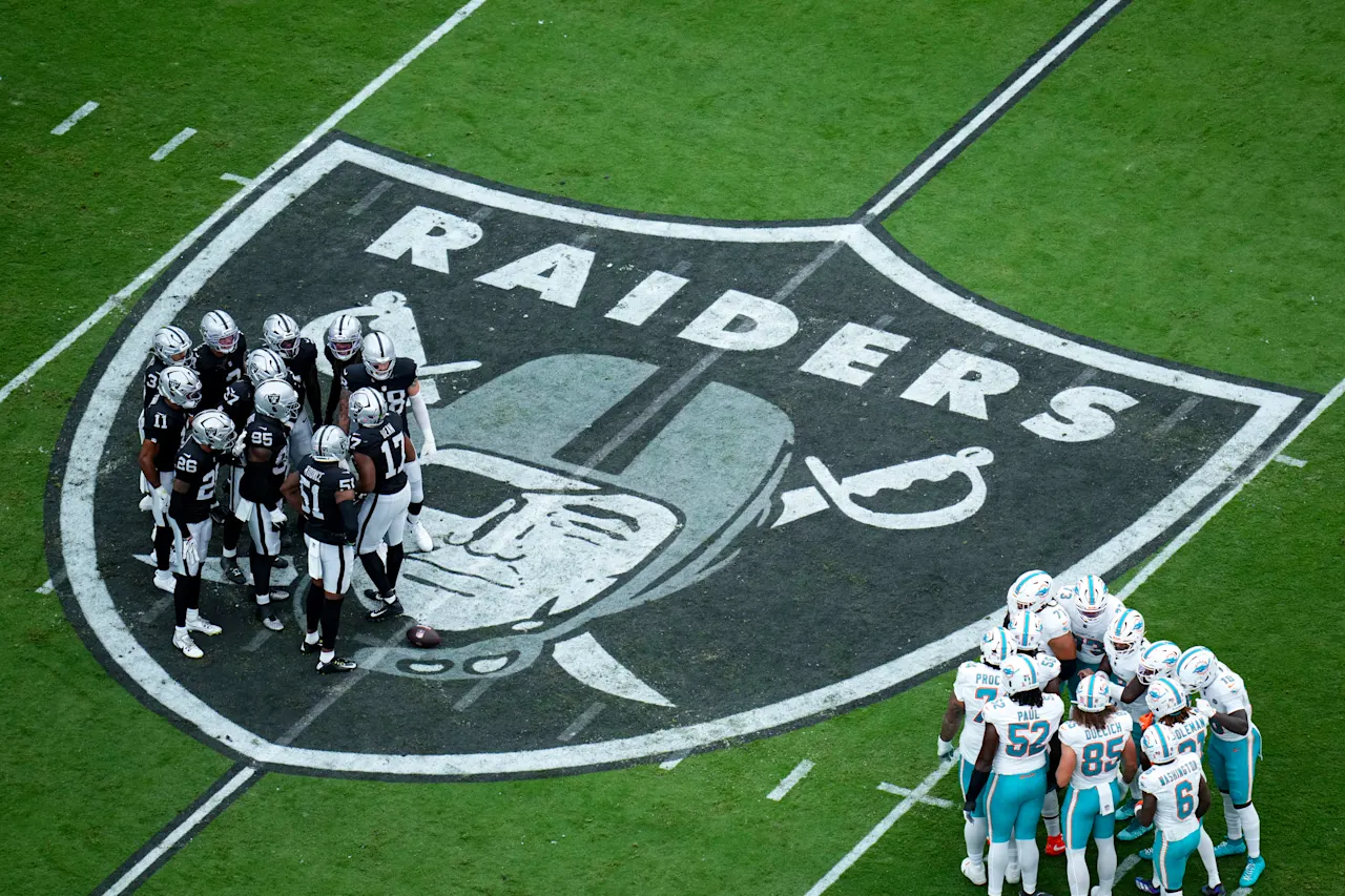 Las Vegas Raiders Defense stand on the Raiders logo in the huddle, as the Dolphins offense do the same