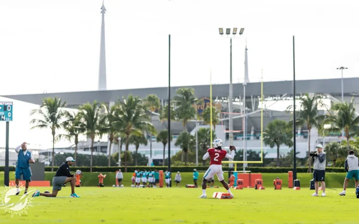 Miami Dolphins QB Malik Willis throws the ball in training, with Hard Rock Stadium in the background